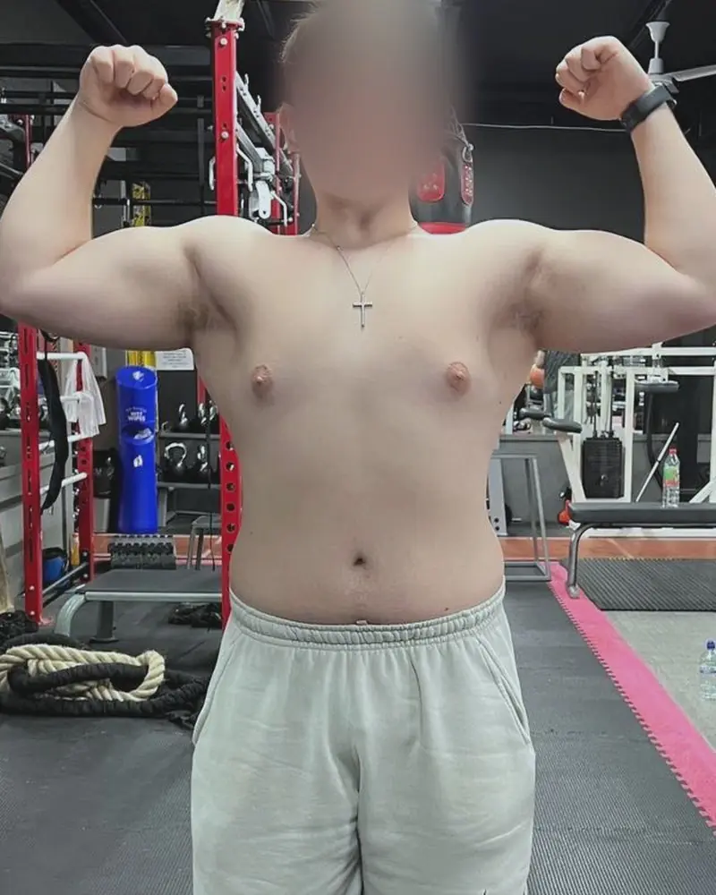 Pi noy at the start: front double biceps pose in a gym, face blurred.